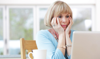 Vrouw zorgelijk kijkend achter een laptop