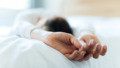 Vrouw ligt op bed met gestrekte armen