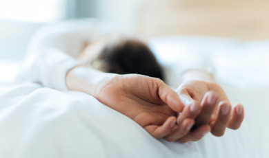 Vrouw ligt op bed met gestrekte armen