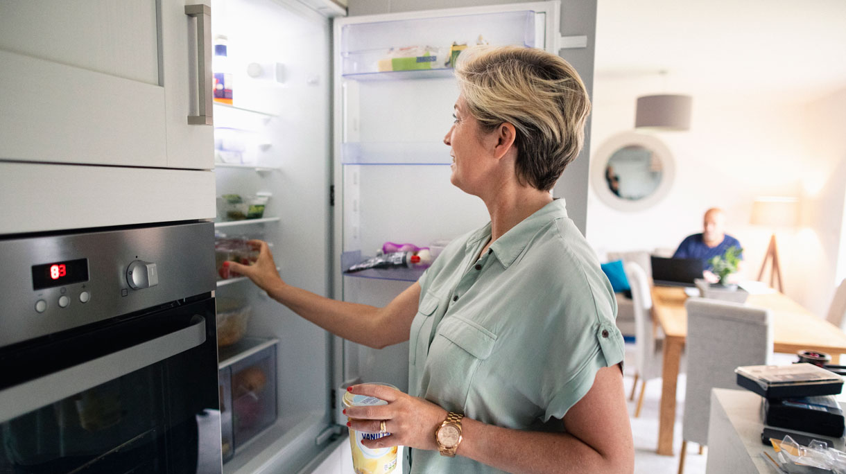 Vrouw haalt eten uit de koelkast