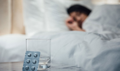 Vrouw in bed met slaapmedicatie op de voorgrond