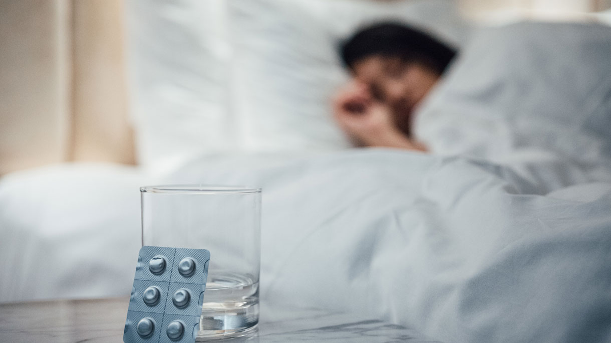 Vrouw in bed met slaapmedicatie op de voorgrond