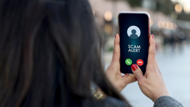 Vrouw met tekst Scam Alert op haar smartphone, phishing en oplichting