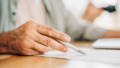 man met pen in hand tekent testament