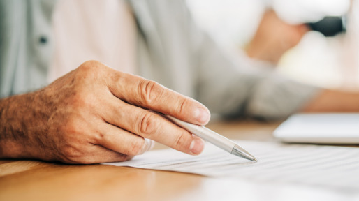 man met pen in hand tekent testament
