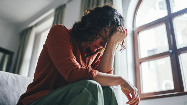 Vrouw zit zorgelijk op bed