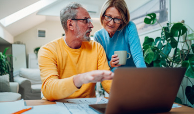 Hypotheek ouder paar bespreekt de cijfers met laptop