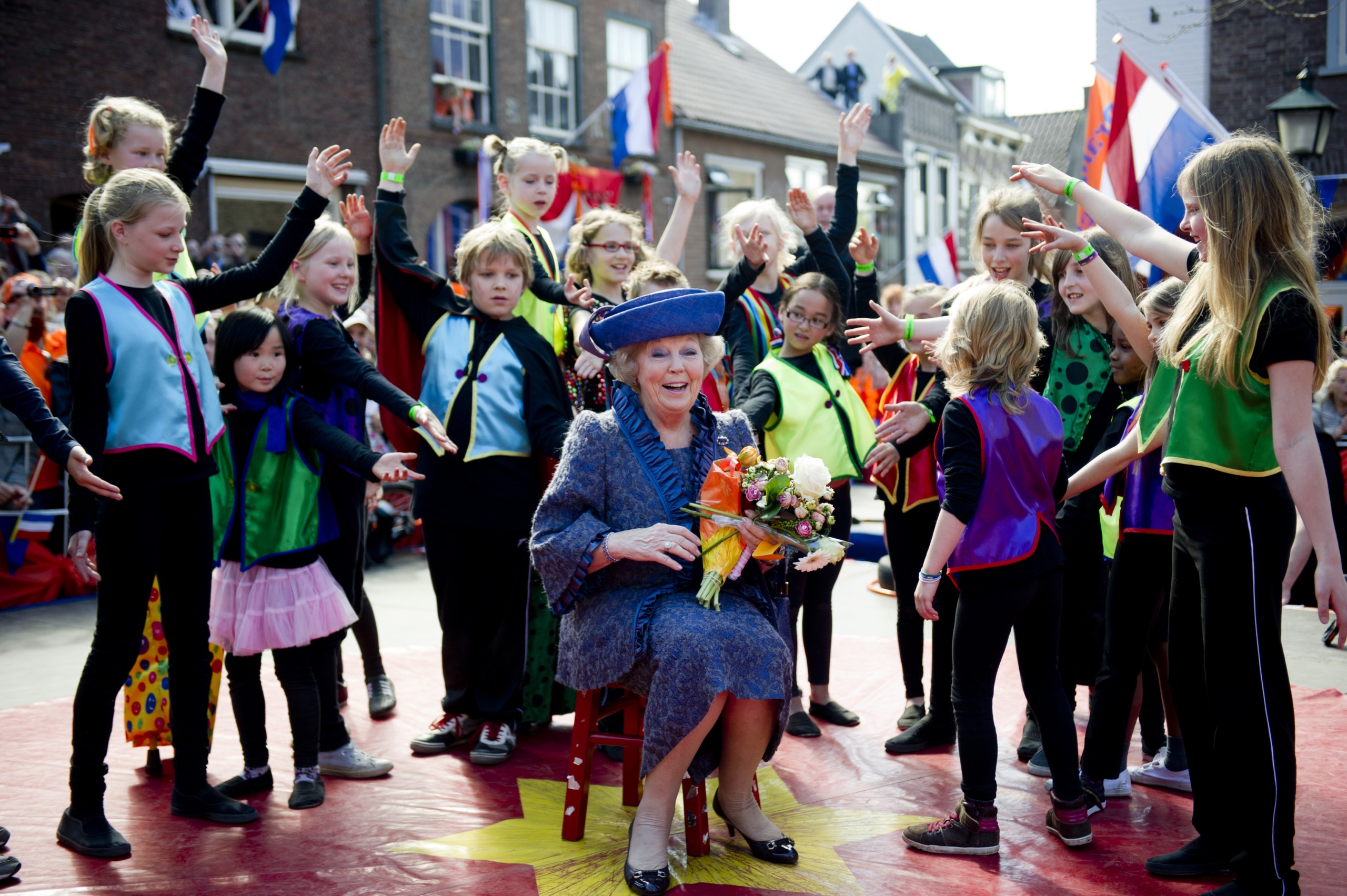 Koningin Beatrix zit tussen kinderen op Koninginnedag
