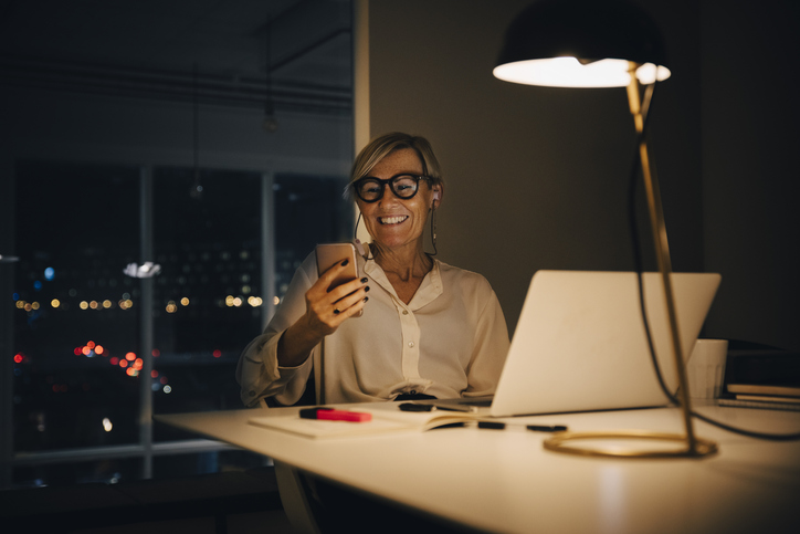 Vrouw is bezig met haar smartphone wifi in te stellen, bureaulamp aan, nacht