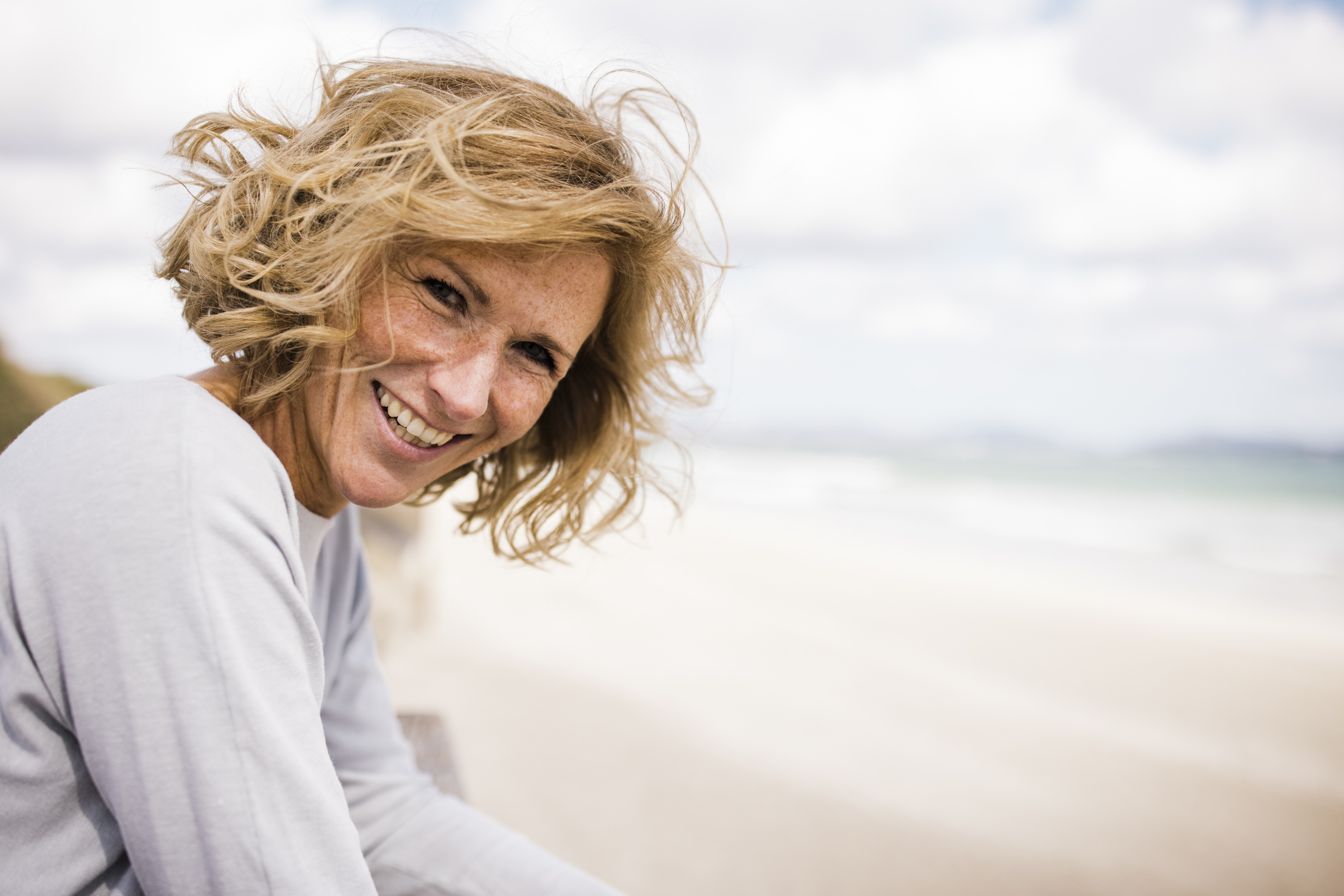 Vrouw aan het strand met lang blond haar