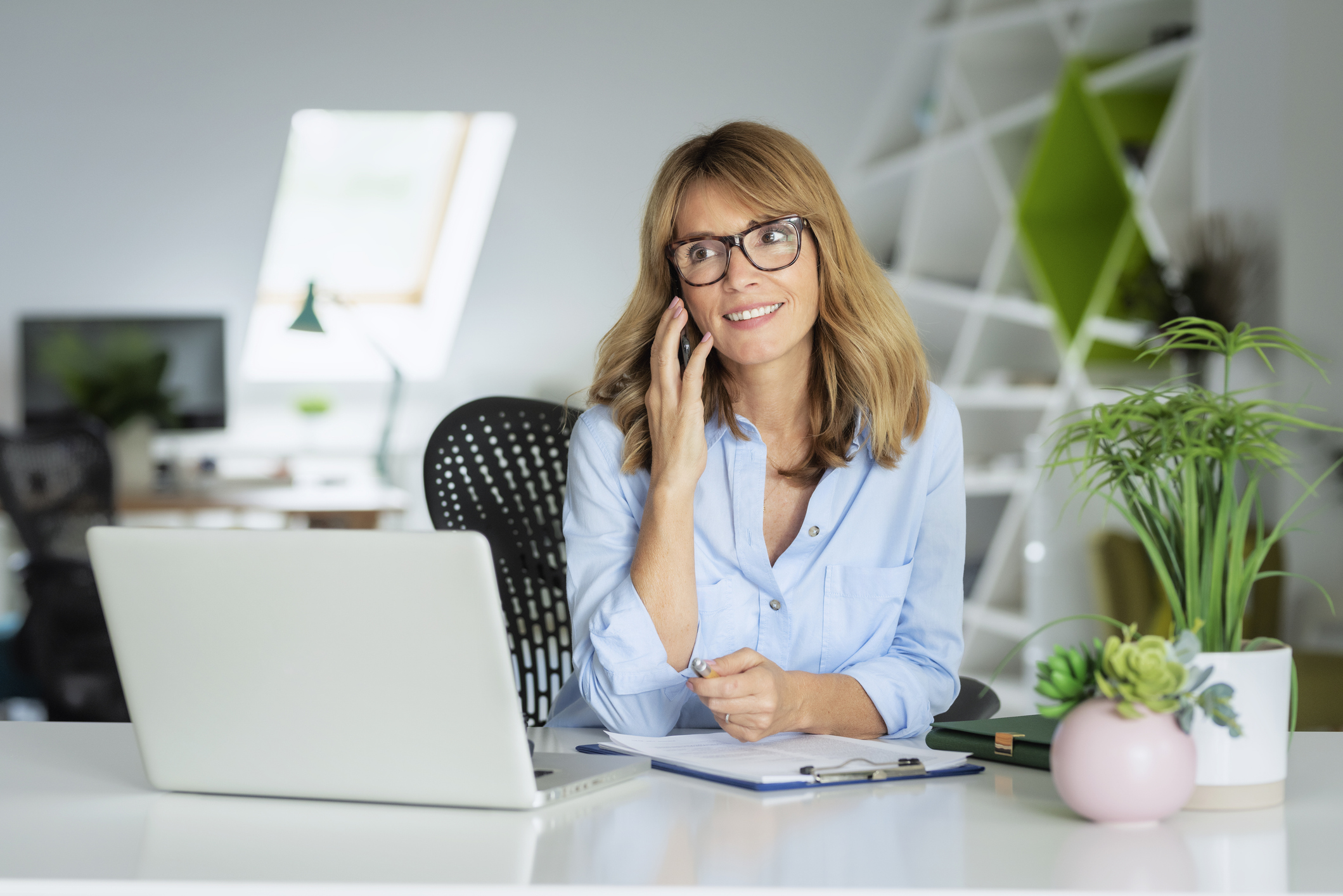 Vrouw is aan de telefoon in haar kantoor