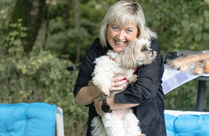 Vrouw knuffelt met klein hondje in haar armen