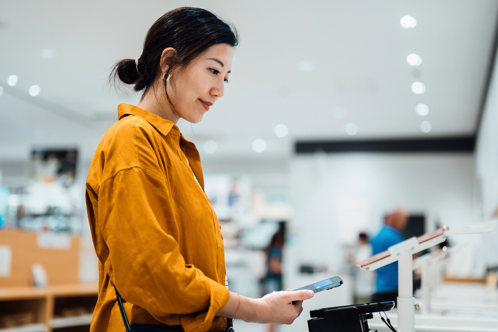 Aziatische vrouw bekijkt tablet in winkel