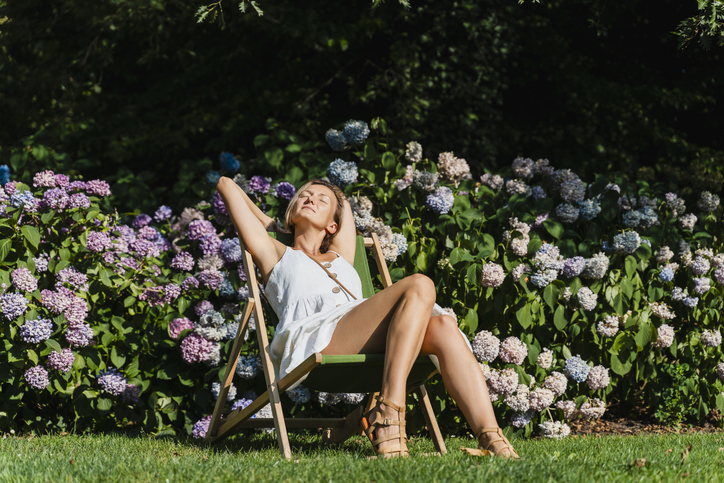 Vrouw zit te zonnen tussen hortensias