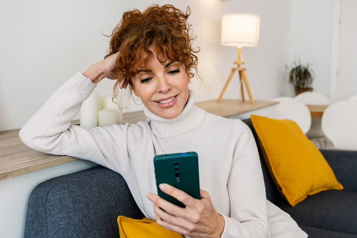 Knappe vrouw met rood haar en smartphone