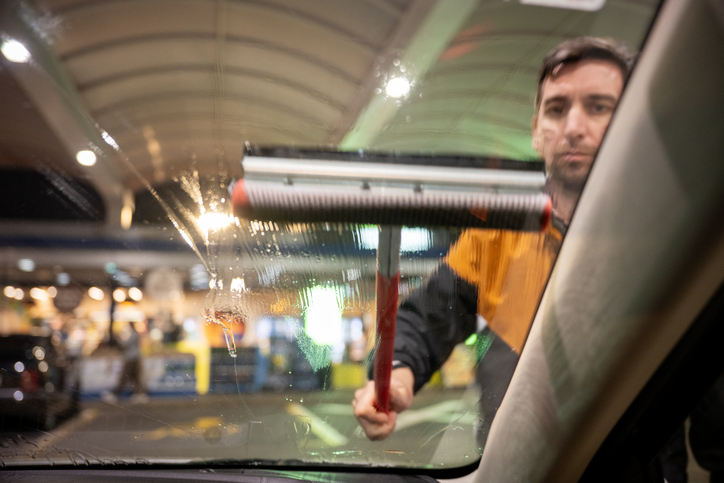 Man wast raam van auto