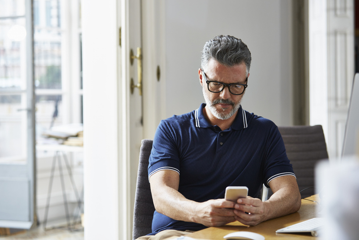 Knappe man is bezig met geldzaken op smartphone