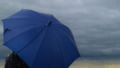 Blue umbrella over a dark stormy cloud
