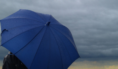 Blue umbrella over a dark stormy cloud